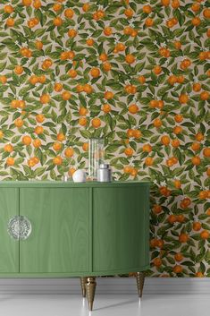 a green cabinet in front of a wall with oranges on it