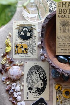 some cards are sitting on a table next to a bowl with rocks and flowers in it