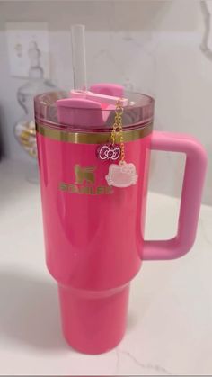 a pink coffee cup with hello kitty on the lid and gold chain hanging from it