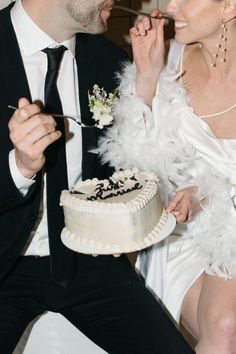 a man and woman sitting next to each other eating cake