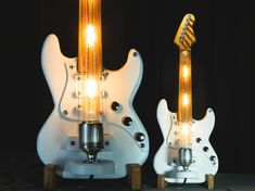 two electric guitars are lit up with light bulbs on their heads and neck, one is white the other is gold