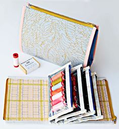 an open zippered pouch filled with different colored threads and sewing supplies on top of a table