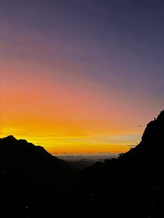 the sun is setting over mountains and hills