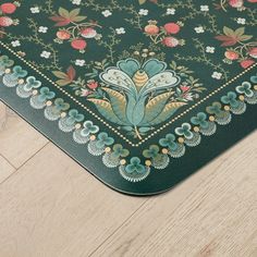 a close up of a mat on the floor with flowers and leaves painted on it