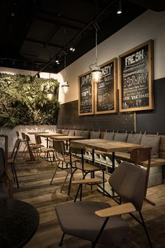 an empty restaurant with wooden tables and chairs in front of chalkboard menus on the wall