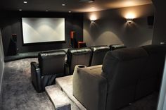 an empty home theater with two recliners in front of the projector screen