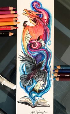 some colored pencils are next to an art book with a bird on it's cover