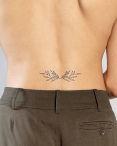 the back of a woman's body with leaves on her left side and an arrow tattoo