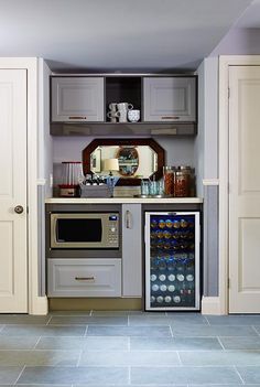 a kitchen with grey cabinets and an oven in the corner next to a wine cooler