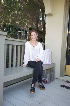 a woman sitting on a bench in front of a house