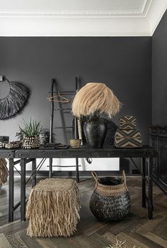 a table with two vases and some plants on it in front of a gray wall