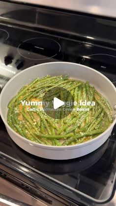 a white bowl filled with green beans on top of an oven