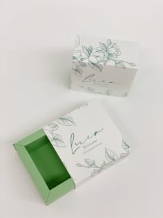 an open green box sitting on top of a white table next to a cardboard box