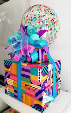 a colorful gift box is wrapped in bright colors and has a balloon attached to it