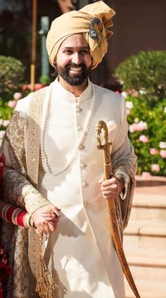 a man in a turban and white outfit holding a large snake on his arm