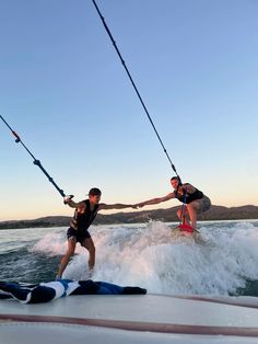 two people on water skis being pulled by a boat while another person holds onto the rope