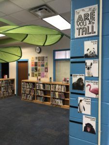 the inside of a library with several bookshelves and posters on the front wall