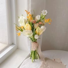 a bouquet of flowers sitting on top of a table next to a window sill