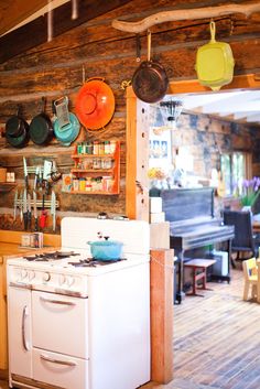 a kitchen with an oven, stove and several pots hanging on the wall above it