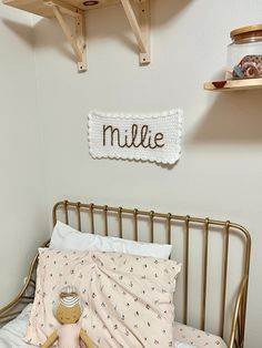 a small child's bed with a teddy bear on it and a name sign above the headboard