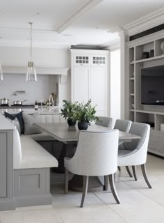 a kitchen with a table, chairs and a television in the center is seen from across the room