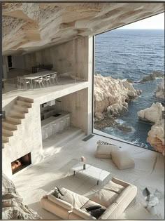 a living room with an ocean view and stairs leading up to the top floor is shown