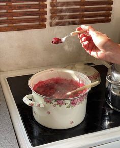 a person is spooning food out of a pot on top of a gas stove