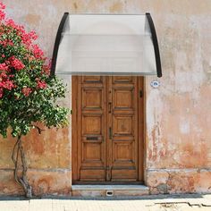 an old building with a wooden door and flower pot on the sidewalk next to it