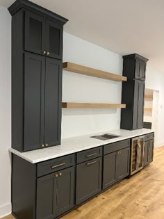 an empty kitchen with black cabinets and white counter tops