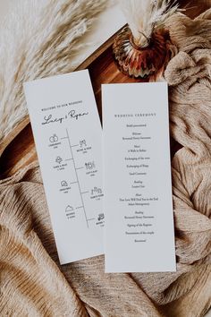 two wedding programs on top of a blanket next to a feathery fan and flower