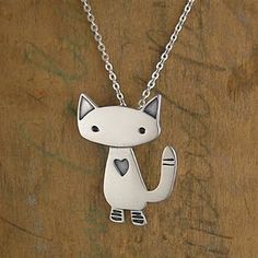 a silver cat with a heart on it's chest sitting on a wooden surface