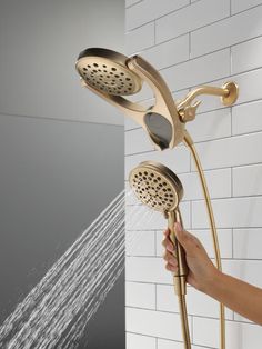 a person is holding the shower head in their hand and it's running water