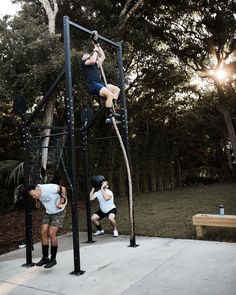 two men are climbing up and down on the ropes in an obstacle course at a park