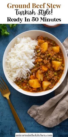 a bowl filled with stew and rice on top of a blue table next to a fork