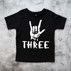 Three Rock on Birthday Shirt, 3rd Rock n Roll Birthday Tee, 3rd Birthday Boy outfit, Three year old Shirt, Born to Rock Theme Please read all the info before placing your order. The price you see is per shirt, please read the size chart in the last pictures of listings before placing your order. How to order a shirt: *Select the STYLE *Select the SIZE *Select the Quantity *Add Personalization *Add to cart *Go back and Repeat for each size (if you need more than one shirt) SHIRTS INFO: *Color: Gr Black Band Merch T-shirt For Birthday, Birthday Band Merch Tops With Short Sleeves, Short Sleeve Band Merch Tops For Birthday, Band Merch Tops For Birthday With Short Sleeves, Black Summer Shirt For Birthday, Black Shirt For Summer Birthday, Three Year Old Birthday Party Boy, 3 Year Birthday Theme Boy, Rock N Roll Birthday