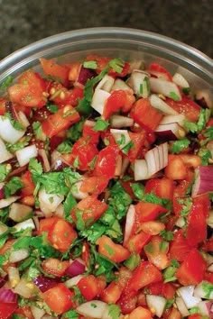 a metal bowl filled with chopped vegetables and garnished with cilantro sauce