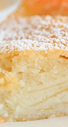 a piece of cake with powdered sugar on top and oranges in the background