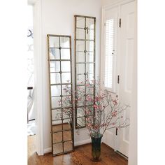 a vase with flowers in it sitting next to two mirrors on the wall near a door