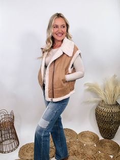 Camel Tan Suede Vest with Sherpa Trim Upgrade your winter wardrobe with our Camel Tan Suede Vest with Sherpa Trim. This chic vest is perfect for a stylish snow day outfit, offering a luxurious look and feel that will make you stand out. The soft suede material in a rich camel tan color is complemented by plush fur trim at the edges, giving it a high-end, sophisticated vibe. With a zipper front and side pockets, this vest combines practicality with elegance. The relaxed fit ensures comfort, makin Beige Vest For Cold Weather In Winter, Beige Vest For Cold Weather And Winter, Beige Vest For Winter Cold Weather, Beige Winter Vest For Cold Weather, Beige Vest For Layering, Beige Vest For Cold Weather In Fall, Trendy Cold Weather Vest Outerwear, Trendy Vest For Cold Weather, Sleeveless Beige Outerwear For Layering