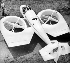 an old black and white photo of a model airplane on the ground with two men looking at it