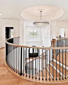 a spiral staircase in a home with white walls and wood floors, chandelier and windows