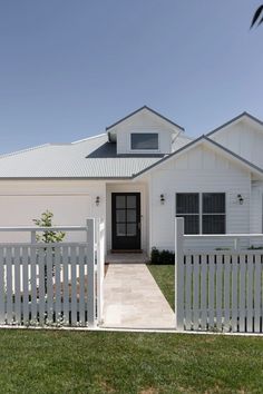 a white house with a black door and fence