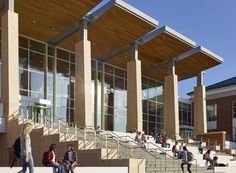 several people are walking up and down the stairs in front of a building with many windows