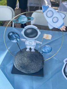 a small spaceman figurine sitting on top of a blue cloth covered table