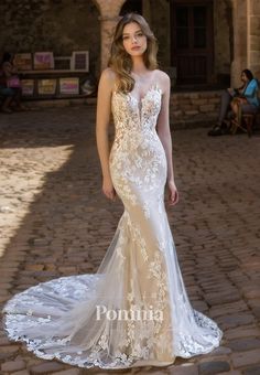 a woman in a wedding dress standing on a cobblestone walkway with her hand on her hip