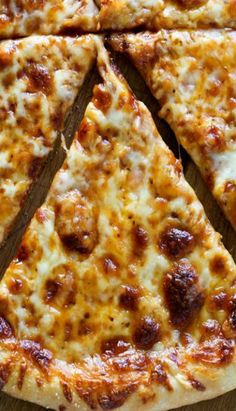 a close up of a slice of pizza on a wooden table with one piece missing