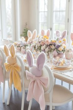 some bunny ears are sitting on the back of chairs at a table with plates and napkins