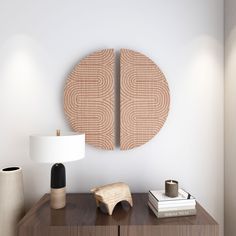 two wooden circles on the wall above a table with books and vases next to it