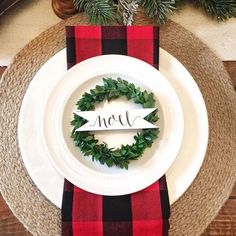 the place setting is decorated with red and black plaid napkins, greenery, and an acorn wreath