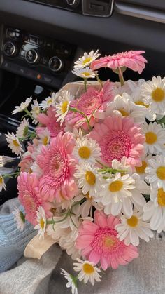 a bouquet of daisies and other flowers in a car